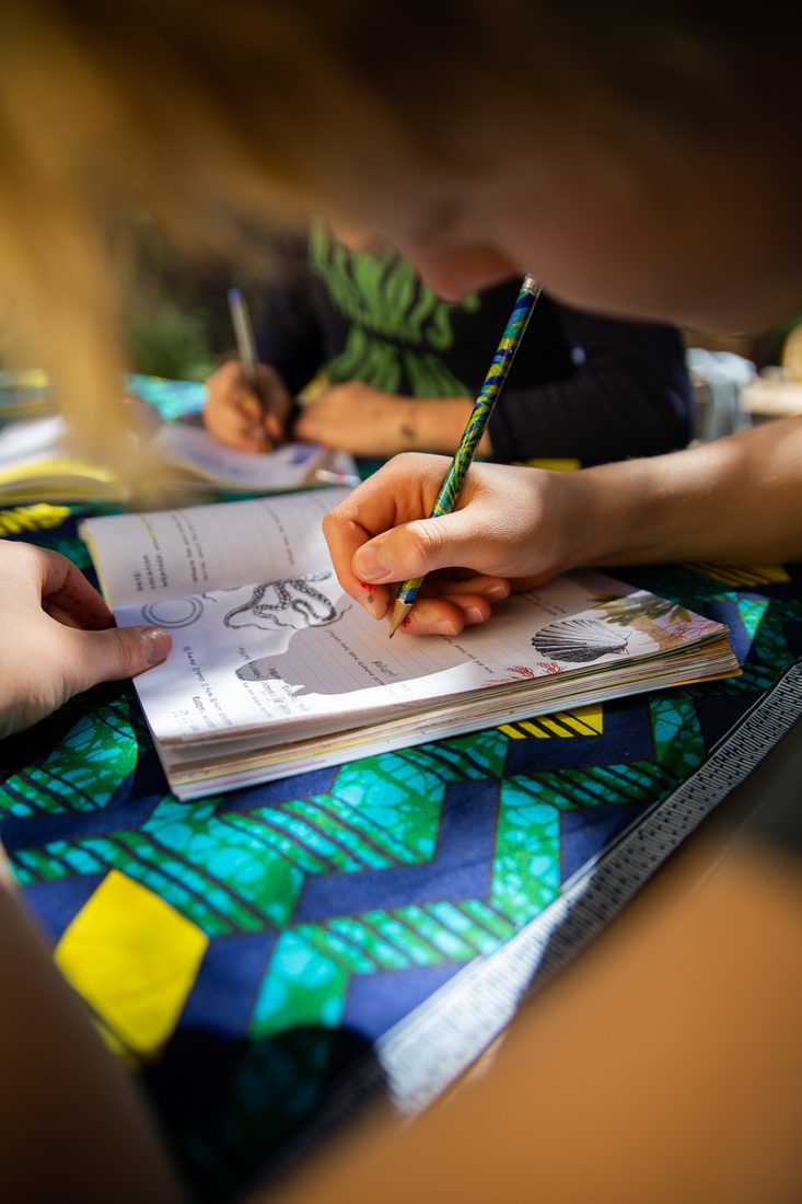 A child writing in the Worldwide Adventure Journal